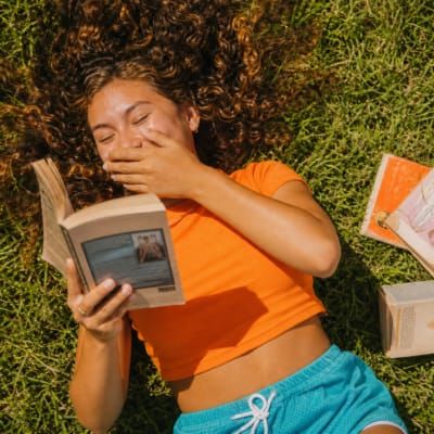 Reader laughing with a book outdoors